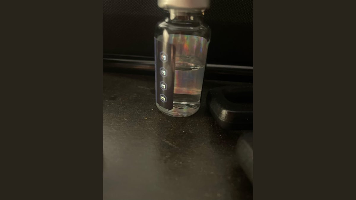 A clear vial of bacteriostatic water rests on a clean, bright laboratory counter.