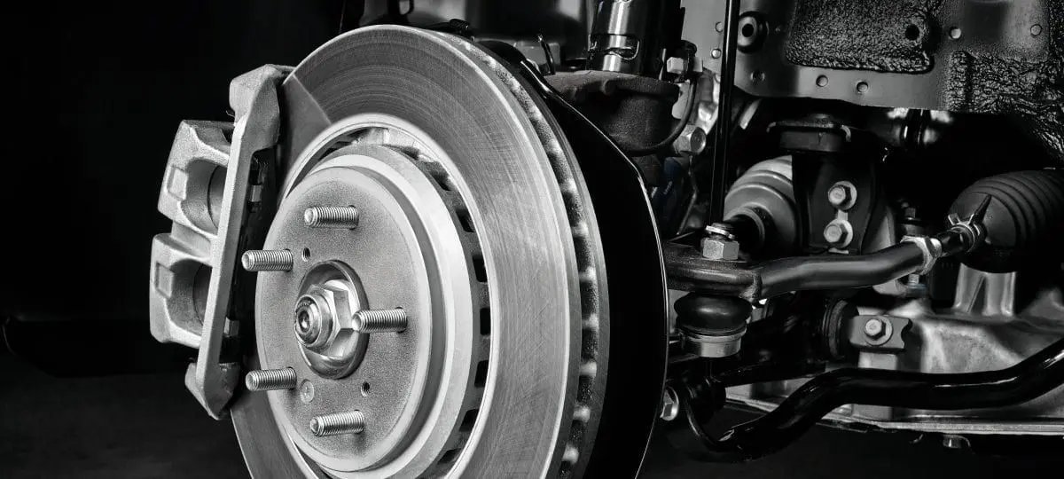 A technician performs professional brake service on a modern Acura inside a clean workshop.