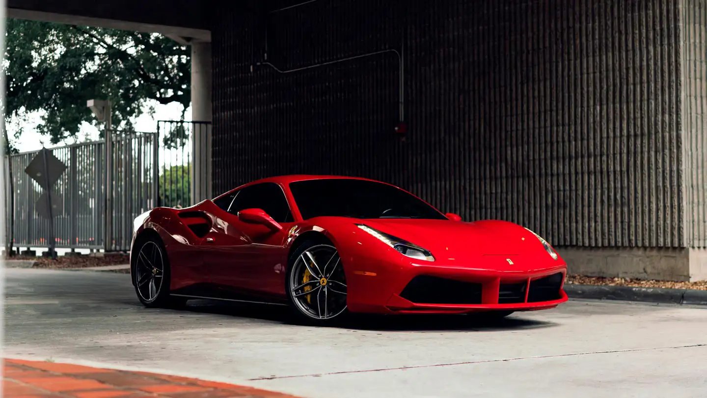 A luxurious red Ferrari parked elegantly on a scenic coastal road during sunset.