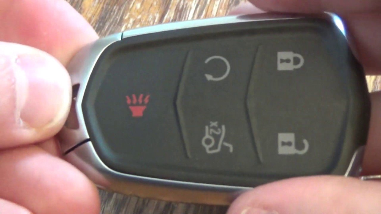 A Cadillac key fob and tools arranged for a battery replacement project.