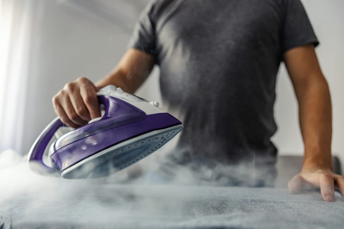 A handheld steamer removing wrinkles from elegant new curtains in a modern home.