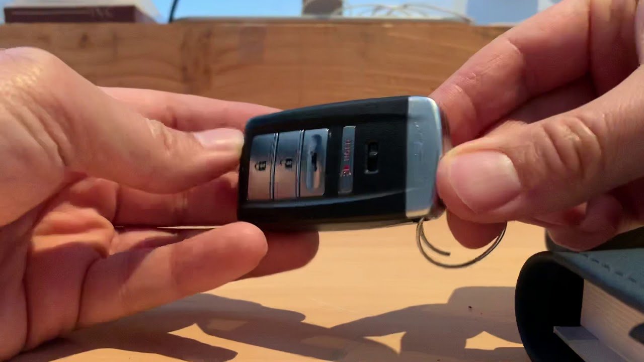 A new battery and tools placed beside an Acura key fob on a workbench.