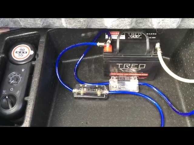 Professional car audio secondary battery installation with thick power cables in an engine bay.
